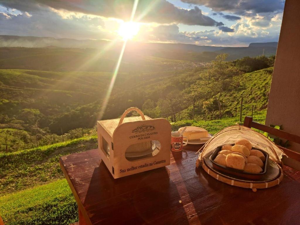 Mesa na varanda com kit de boas-vindas e pão de queijo, de frente para o pôr do sol na Serra da Canastra